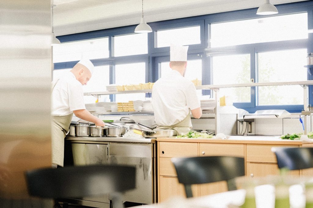 Zwei Köche bei der Arbeit in einer Klinik-Großküche. Kontext: Job-Angebot Küchenhilfe