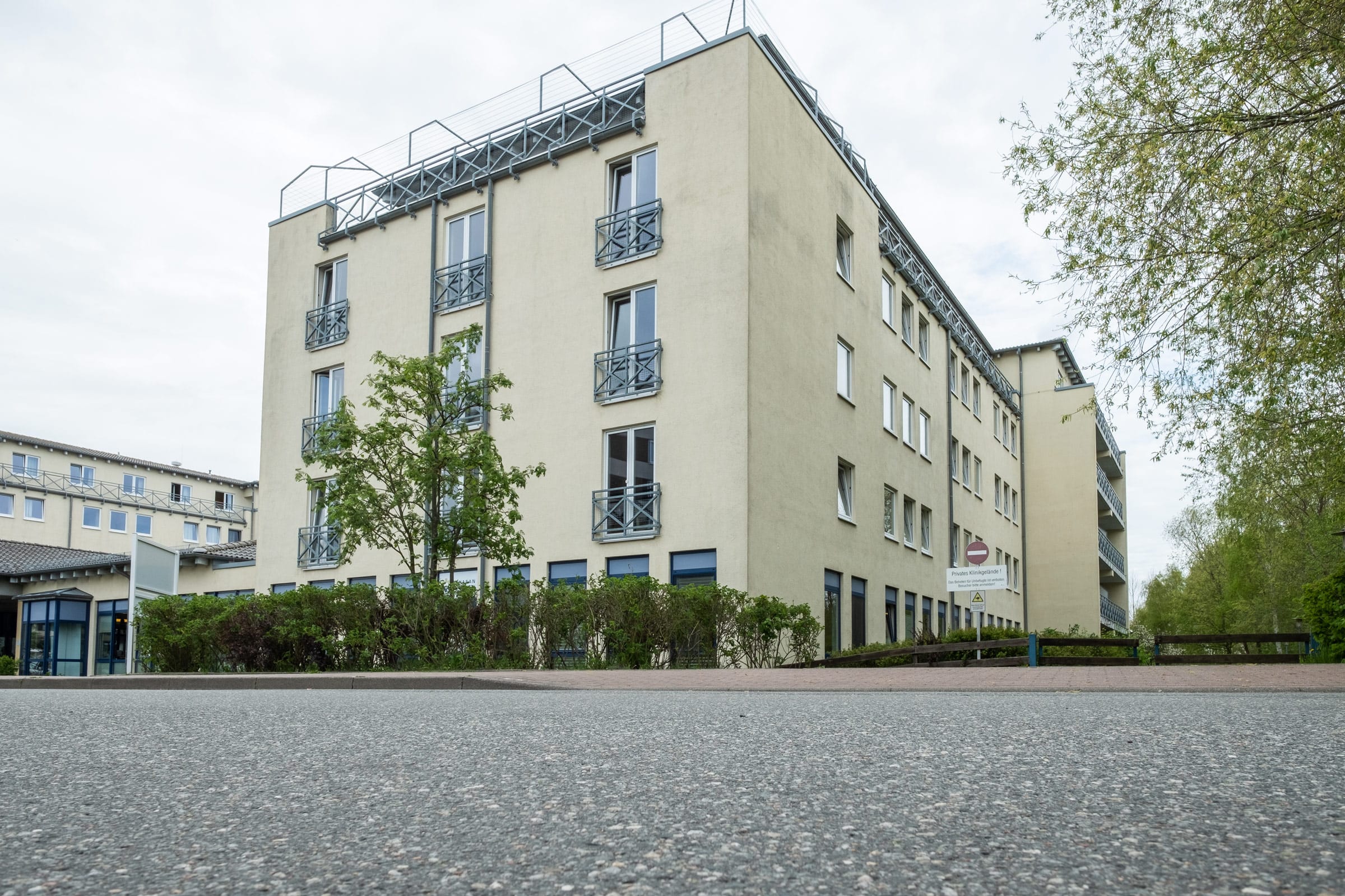 Foto der Ostseeklinik Grömitz, Rehaklinik für Mutter-Kind-Kuren sowie Vater-Kind-Kuren: ein mehrstöckiges, helles Klinikgebäude mit französischen Balkonen und einer gepflegten Grünanlage im Vordergrund.