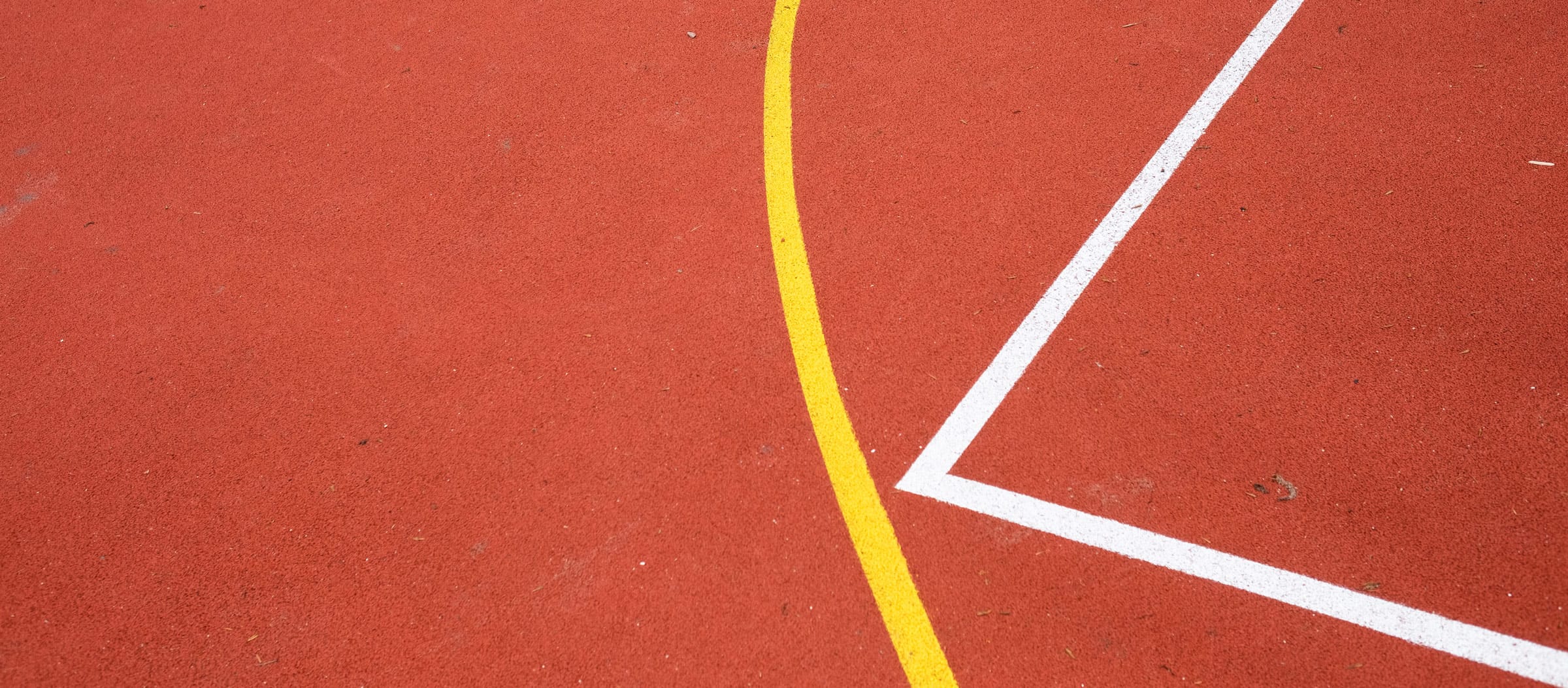 Roter Sportboden mit Tartanbelag und Spielfeldmarkierungen in der Sportaußenanlage der Ostseeklinik Grömitz.